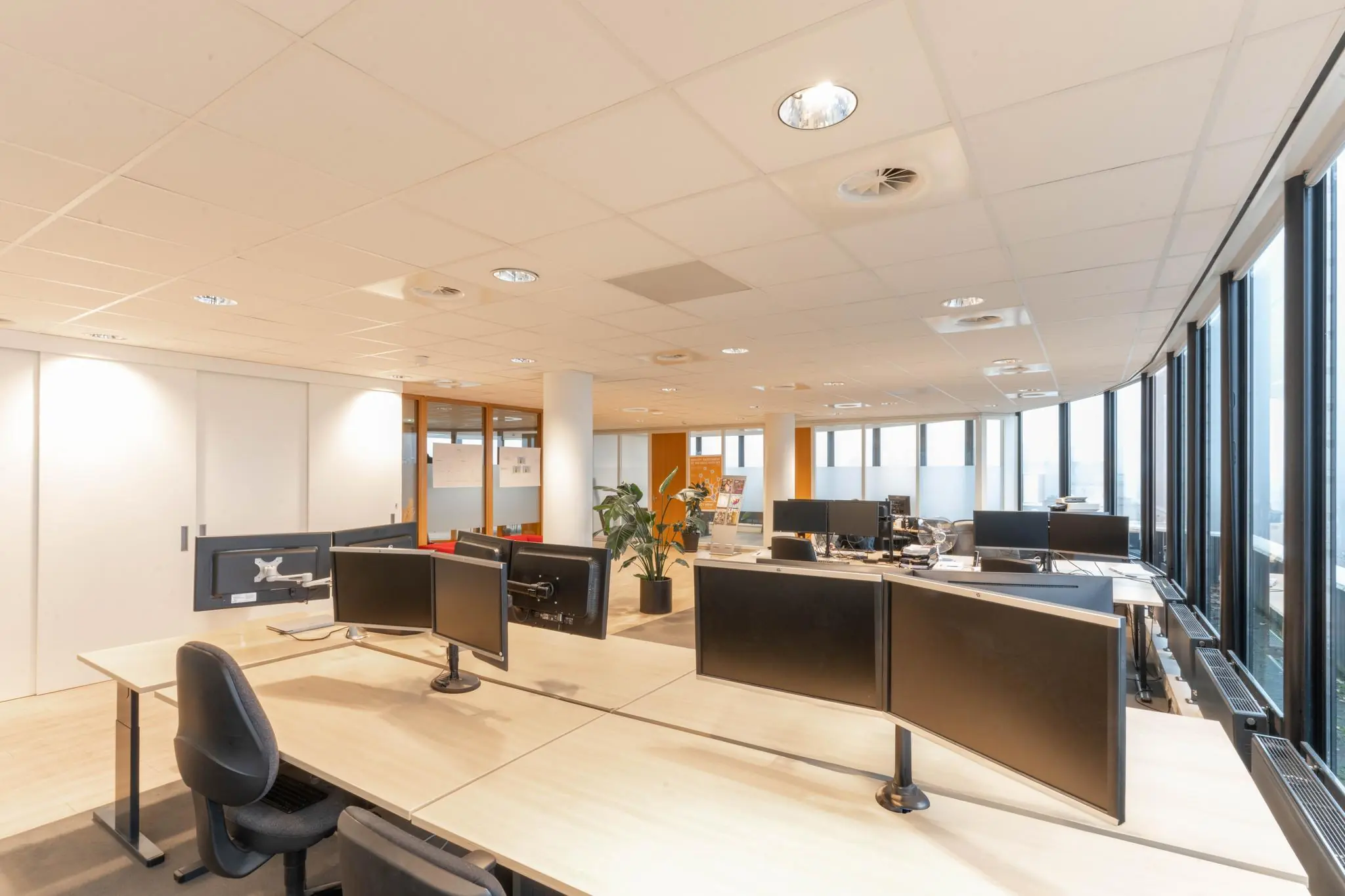 Licht en modern kantoorinterieur aan de 1e Hogeweg met meerdere bureaus, monitoren en grote ramen.